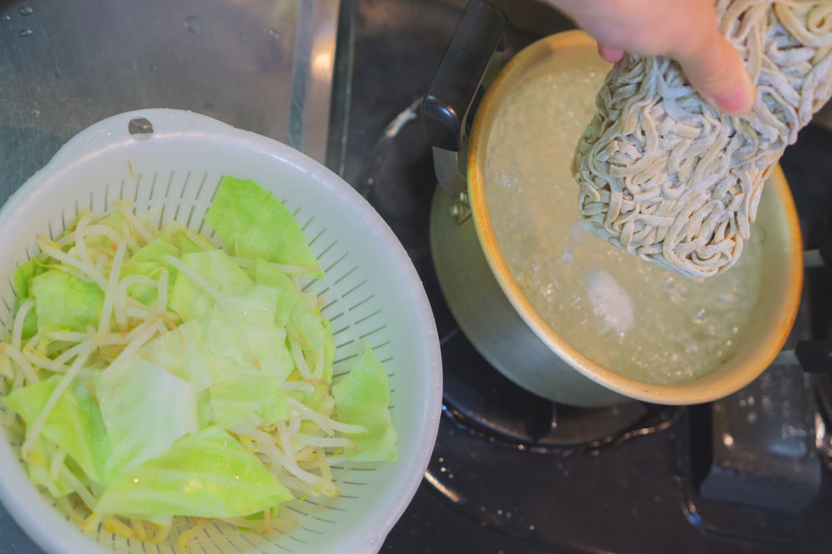 野菜を茹でた鍋にラーメンを入れる